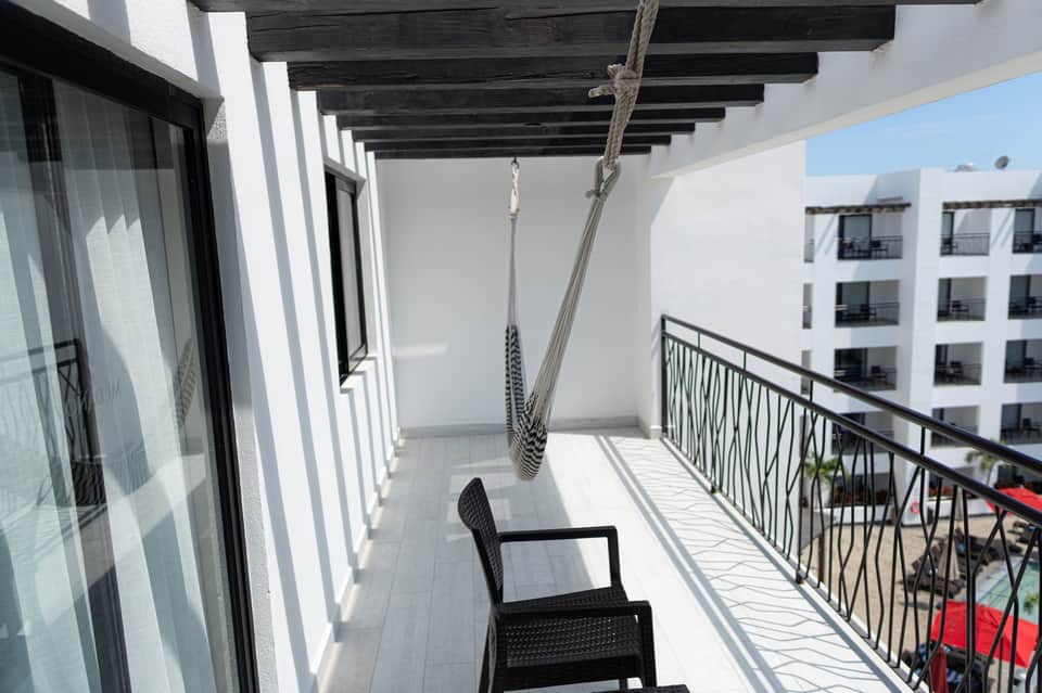 Modern balcony with hammock, black chair, white pergola, and view of residential buildings