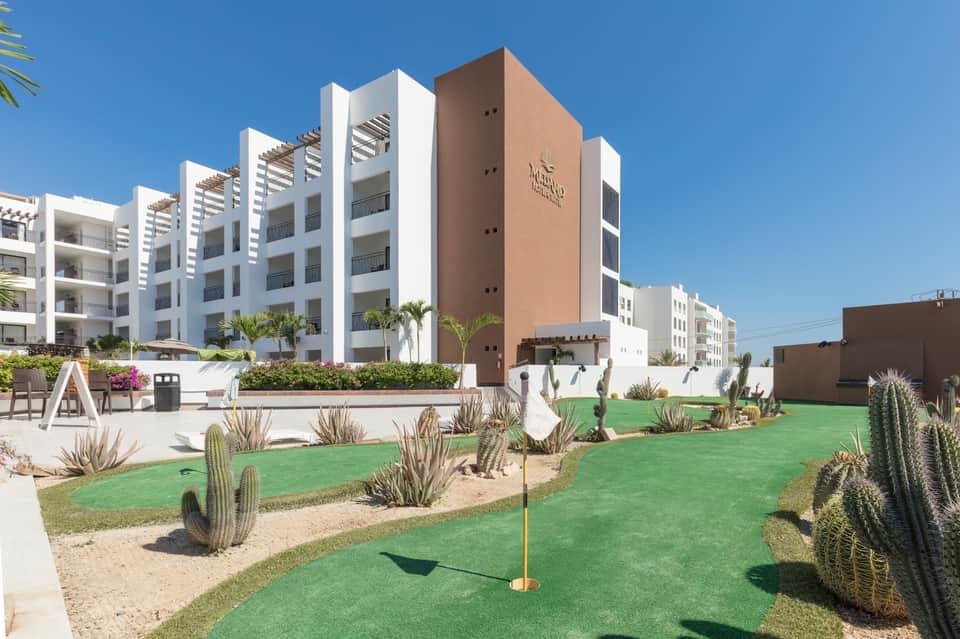 Modern apartment complex with desert landscaping, mini golf course, and cacti
