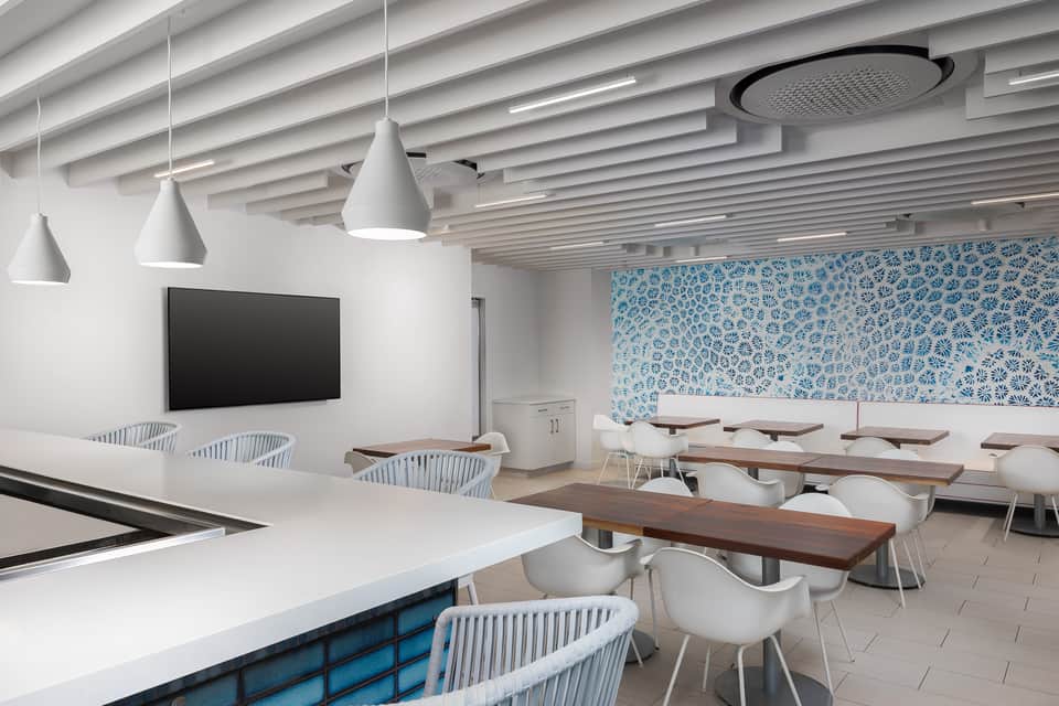Contemporary conference room with white pendant lights, wooden tables, and blue patterned wall art
