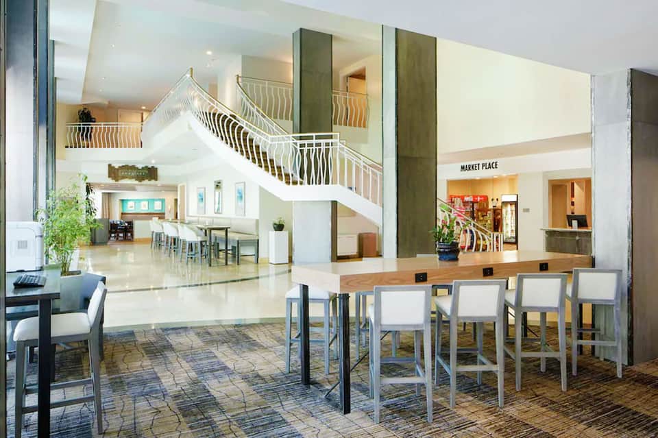 Modern hotel lobby with multi-level atrium, grand staircase, and marketplace entrance with natural lighting