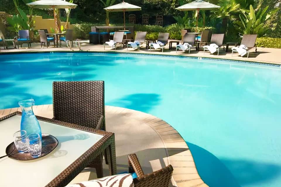 Resort pool with crystal-clear blue water, lounge chairs, umbrellas, and tropical landscaping