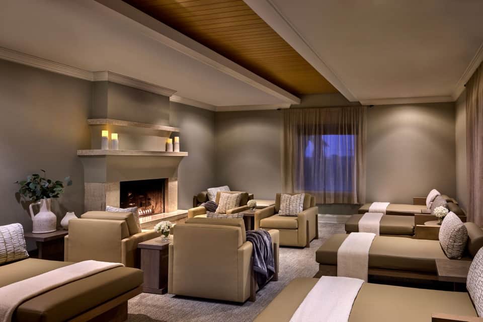 Luxurious spa lounge with fireplace, neutral seating, ambient lighting, and elegant dƩcor