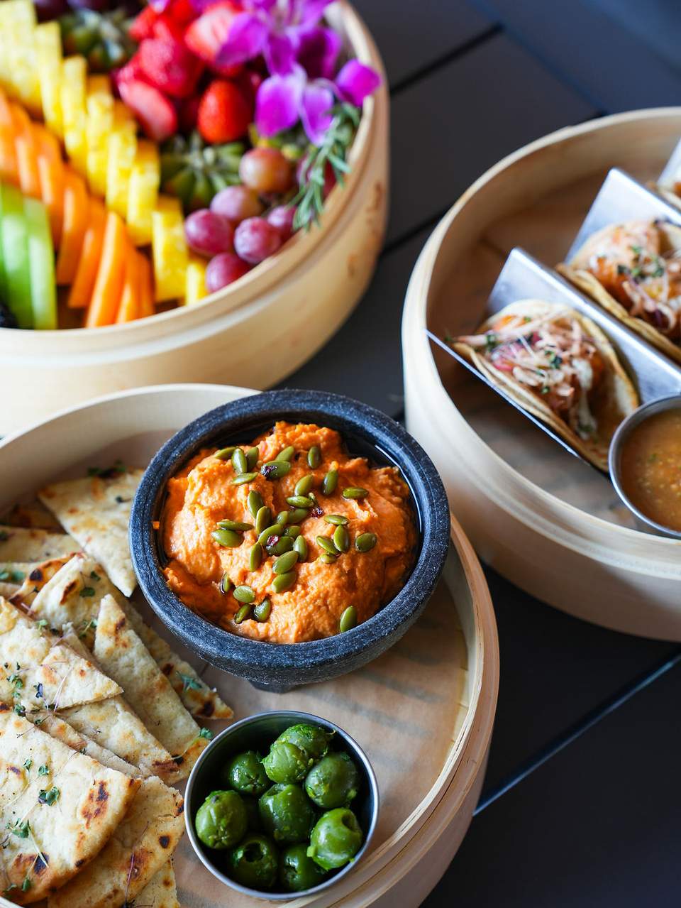 Overhead view of colorful appetizers including vegetable platter, dumplings, curry dip, and flatbread