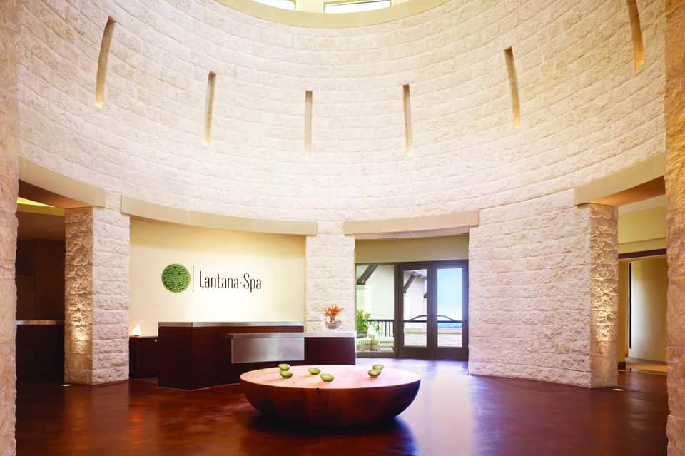 Lantana Spa reception with circular stone counter, curved stone walls, and warm ambient lighting