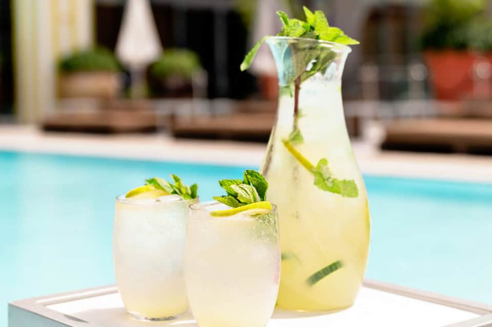 Refreshing mojito pitcher and glasses garnished with mint on poolside table