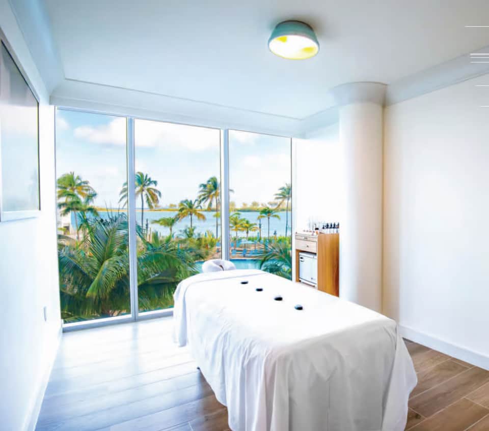 Massage treatment room with ocean and lagoon views through floor-to-ceiling windows
