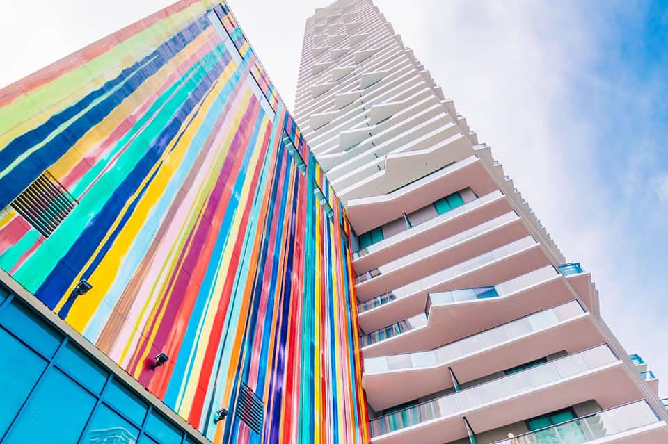 Colorful striped building facade with modern multi-story hotel architecture against blue sky