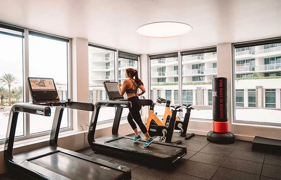 Modern fitness center with treadmills, stationary bikes, and floor-to-ceiling windows