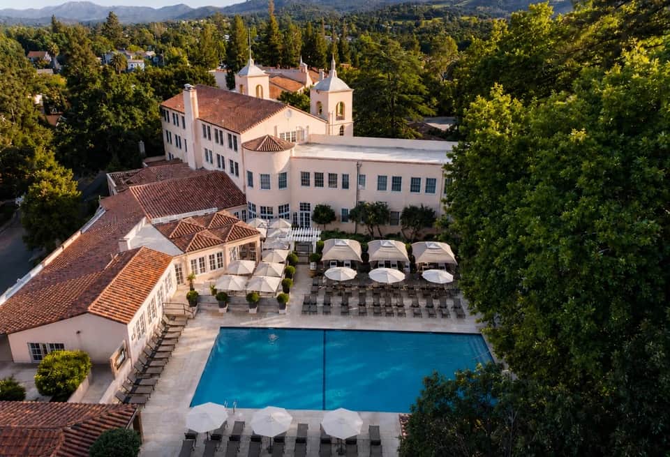 Luxurious resort courtyard with swimming pool, white umbrellas, and Mediterranean architecture