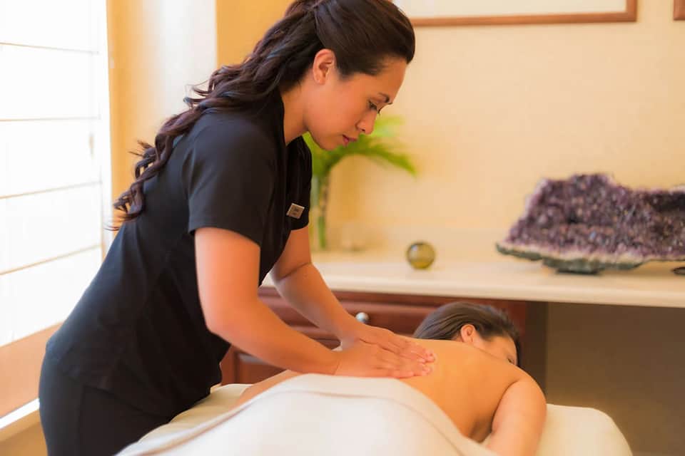 Spa therapist performing massage treatment on client in wellness room