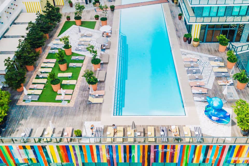 Aerial view of modern hotel pool with colorful striped deck chairs