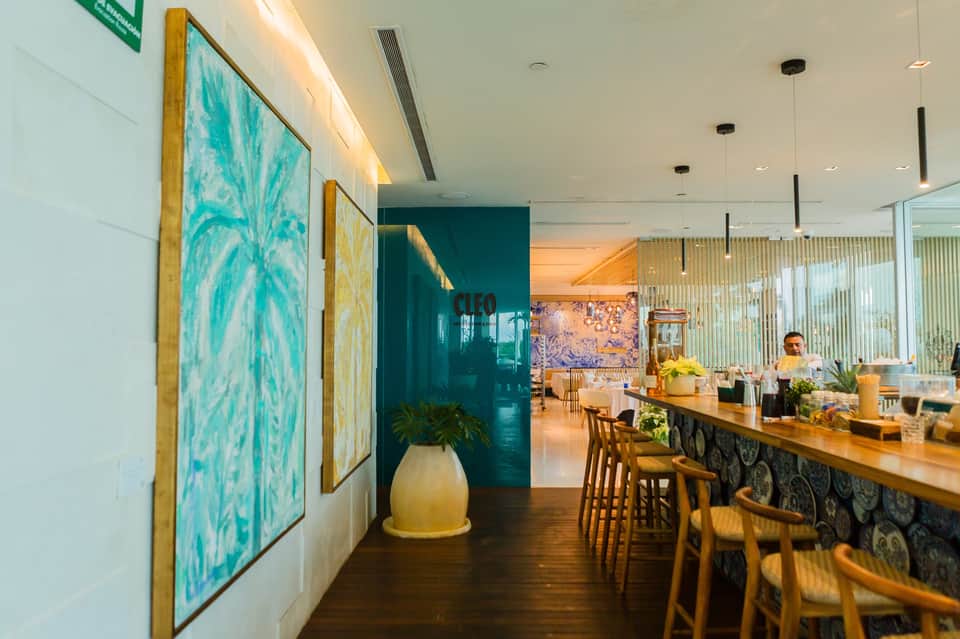 Upscale restaurant interior with turquoise artwork, wooden counter seating, and warm ambient lighting