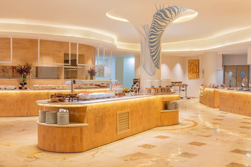 Luxury hotel buffet restaurant with wooden curved counters, zebra artwork, ambient ceiling lights, and marble flooring