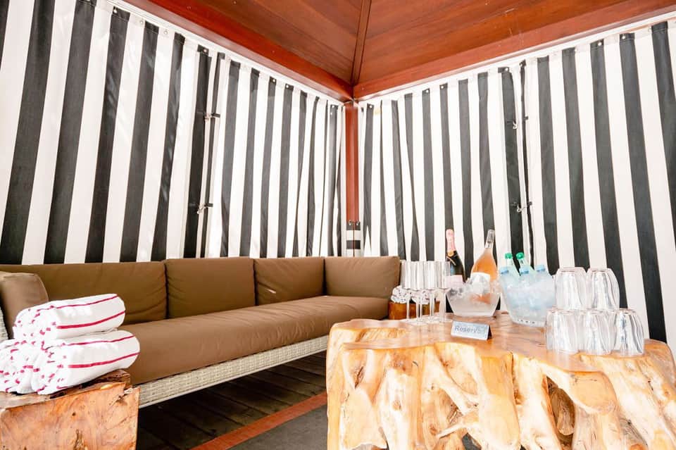 Luxurious lounge area with tan leather seating, striped wall panels, and wooden table with beverages and glassware