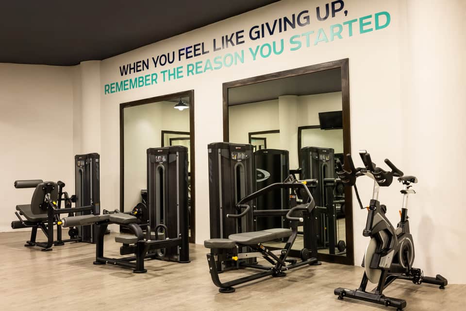 Modern fitness center with cardio equipment, strength machines, mirrors, and motivational wall text