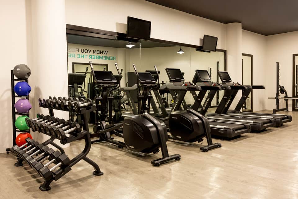 Fitness facility with dumbbell rack, cardio machines, exercise bikes, and mirrored walls