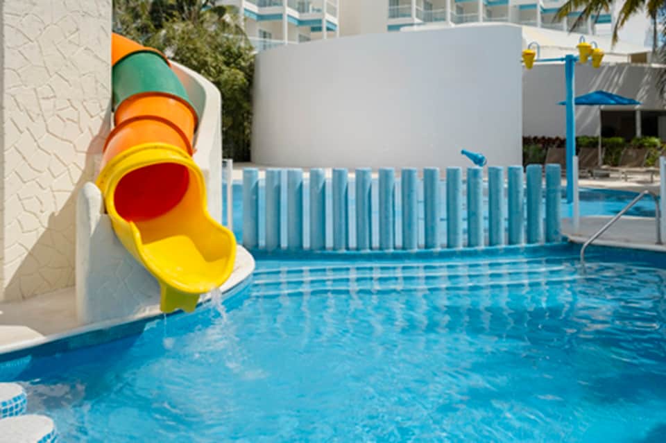 Outdoor kiddie pool with colorful spiral water slide and white safety fencing