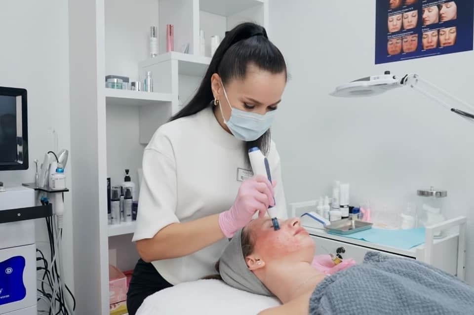 Aesthetician applying facial treatment with handheld device in modern spa clinic