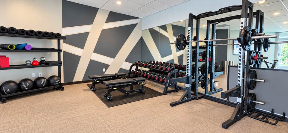 Well-equipped fitness center with dumbbells, weight racks, cable machines, and modern wall design