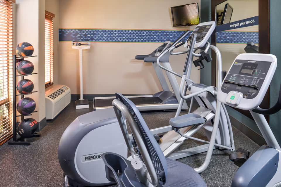 Fitness center with elliptical machine, exercise bike, medicine balls, and motivational wall signage
