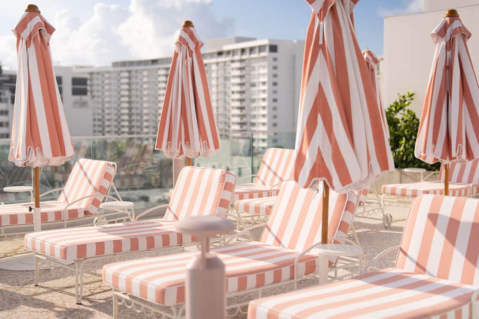 Rooftop lounge with red and white striped umbrellas, deck chairs, and city skyline backdrop