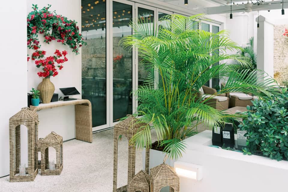 Modern poolside lounge area with wicker furniture, hanging flowers, and tropical plants