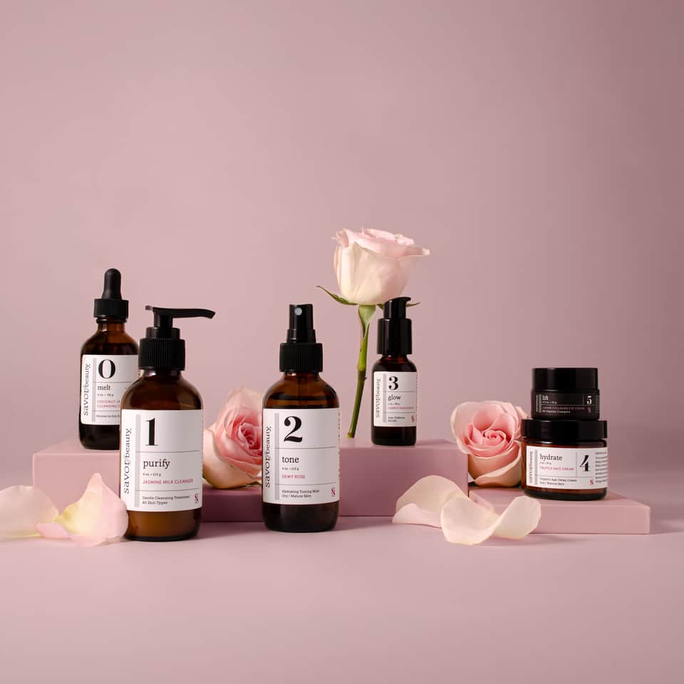 Savor Beauty five-step skincare product line with amber bottles and pink roses