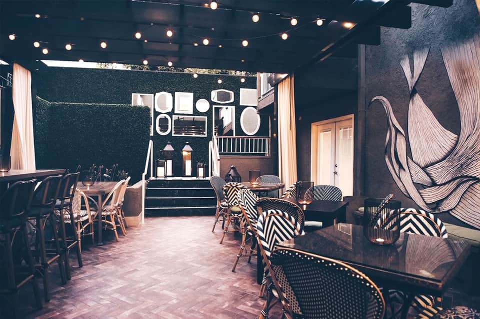 Modern event space with dark walls, string lights, zebra-patterned chairs, and artistic wall installations