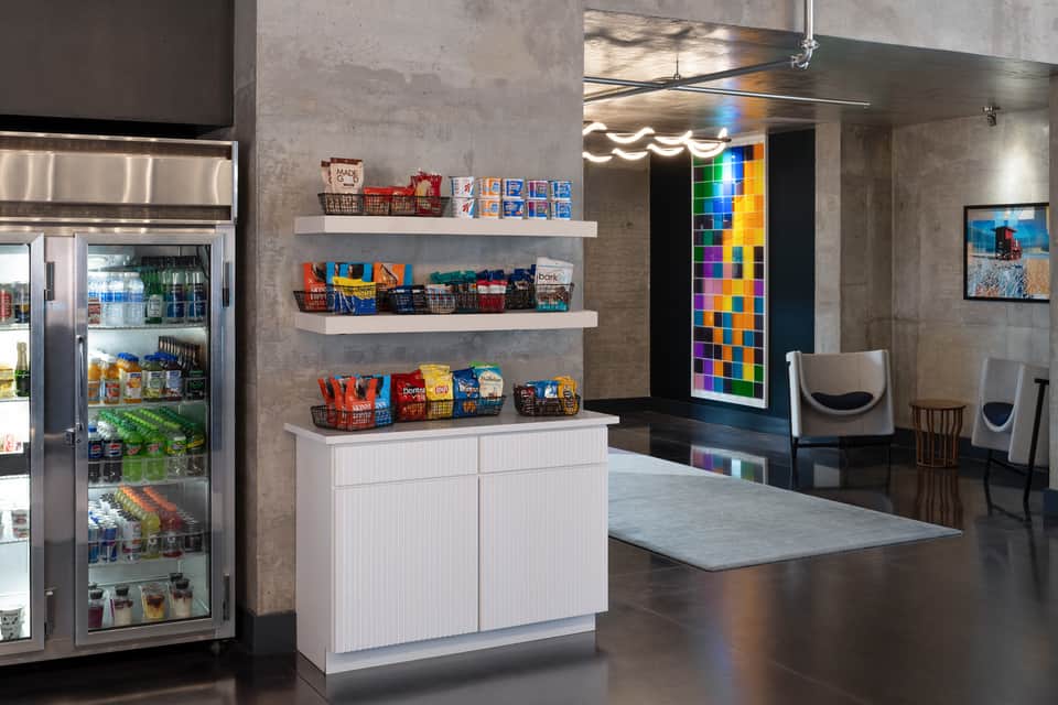 Modern hotel lobby with refrigerated market display, colorful digital art installation, and concrete finishes