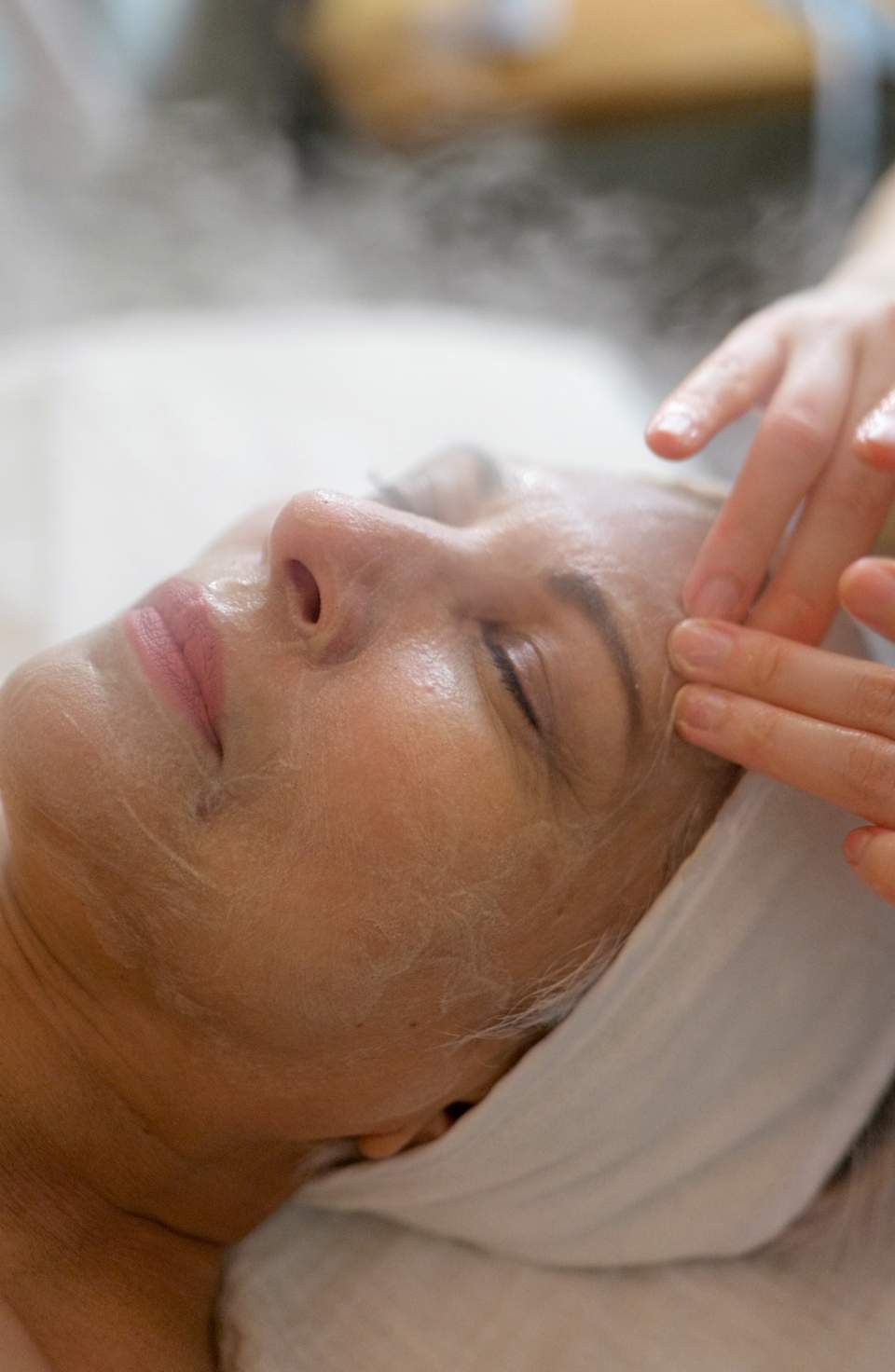 Esthetician applying facial treatment to client's face during spa service