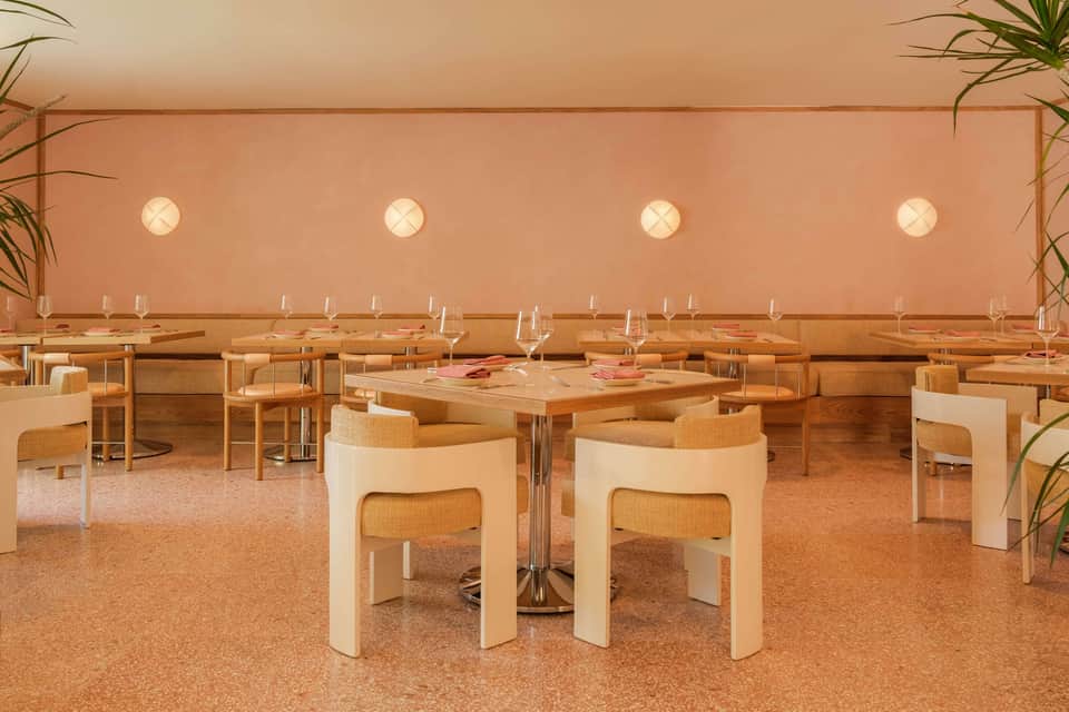 Modern dining room with natural wood tables, cream chairs, and warm ambient lighting