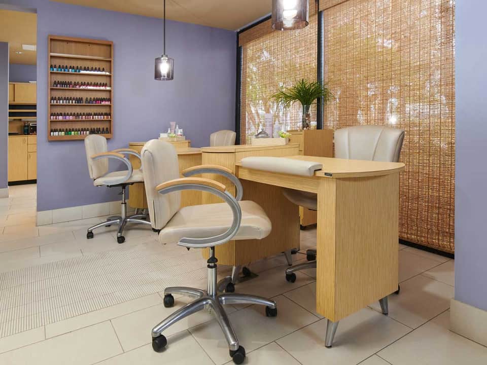 Upscale nail salon with purple walls, wooden manicure stations, and decorative screens