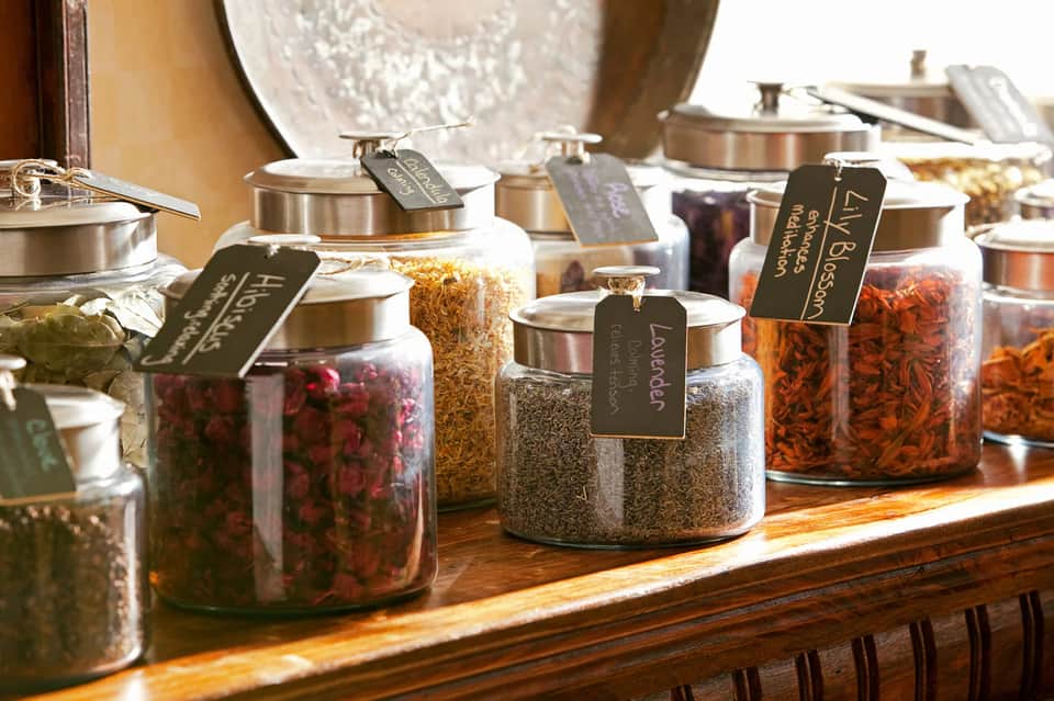 Spa apothecary display with glass jars of dried herbs, flowers, and botanical ingredients with labels
