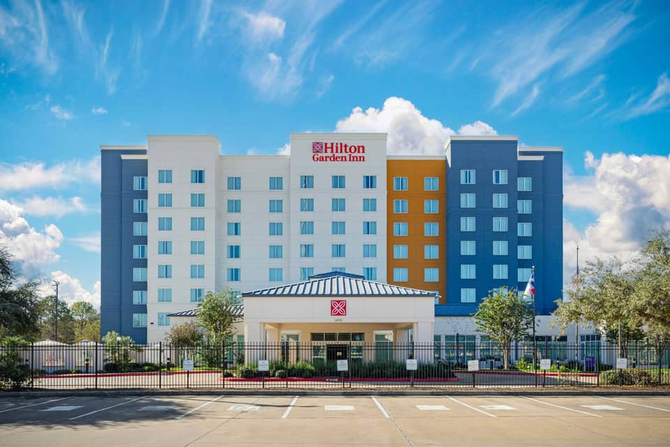 Hilton Garden Inn exterior facade featuring colorful blue, white, and orange sections under clear blue sky
