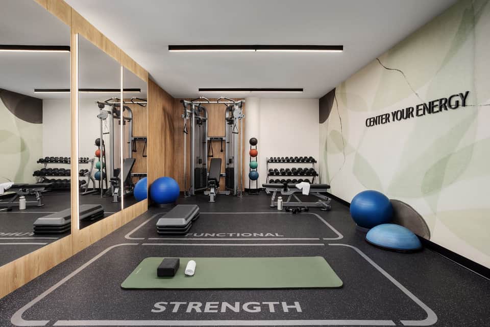Modern gym interior with cardio equipment, free weights, and motivational wall text