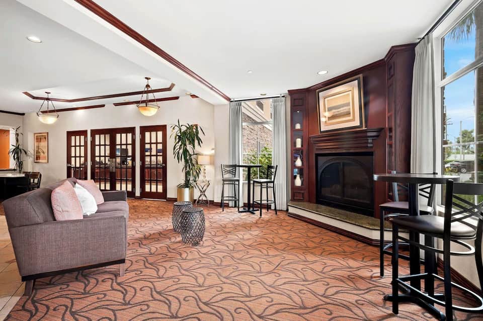 Hotel lobby lounge with fireplace, French doors, seating area, high ceilings, and large windows