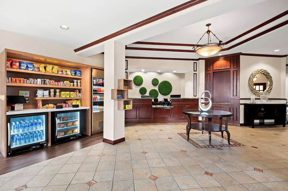 Hotel lobby with snack bar, convenience store shelving, front desk area, decorative mirrors, and exposed beams
