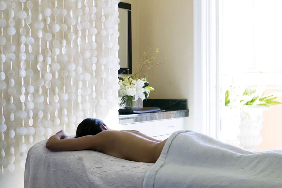 Spa treatment room with person lying face down on massage bed near window