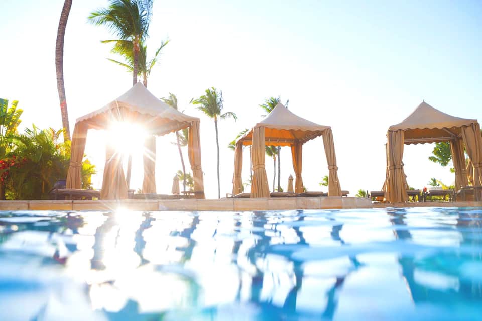 Luxury resort pool with elegant cabanas and palm trees at golden hour