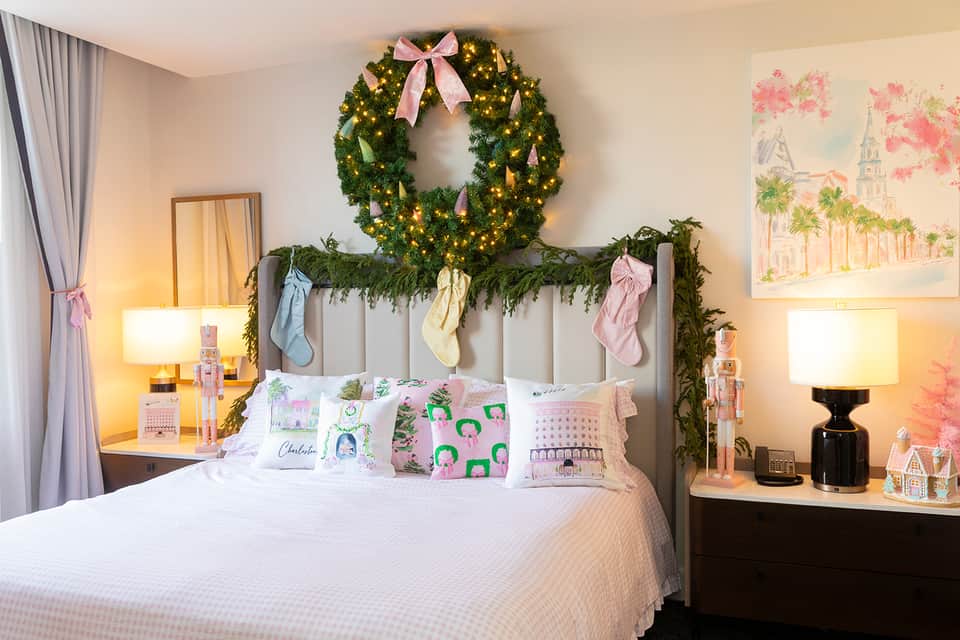 Bedroom with decorated headboard featuring garland and pink bows, matching wreath above, and holiday pillows
