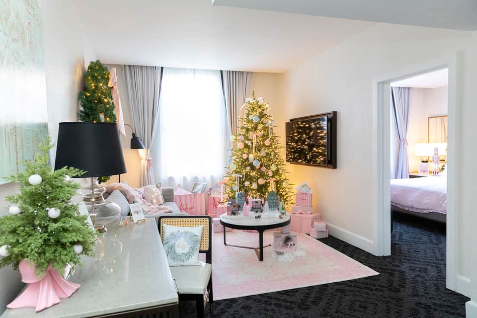 Luxury suite living area with Christmas décor, decorated trees, pink accents, and view into adjacent bedroom