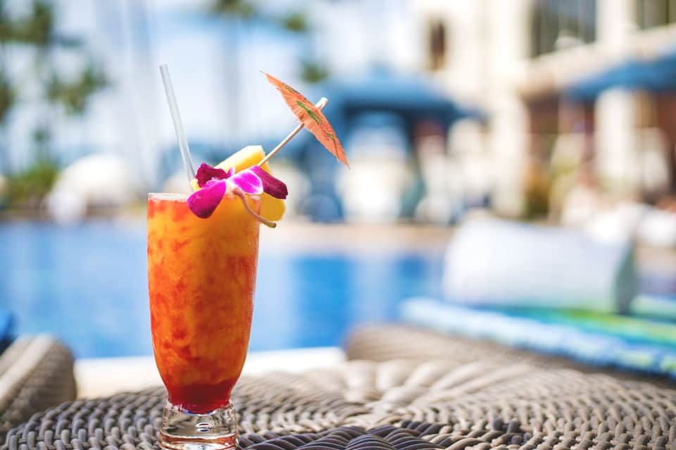 Tropical cocktail with umbrella garnish by poolside resort setting