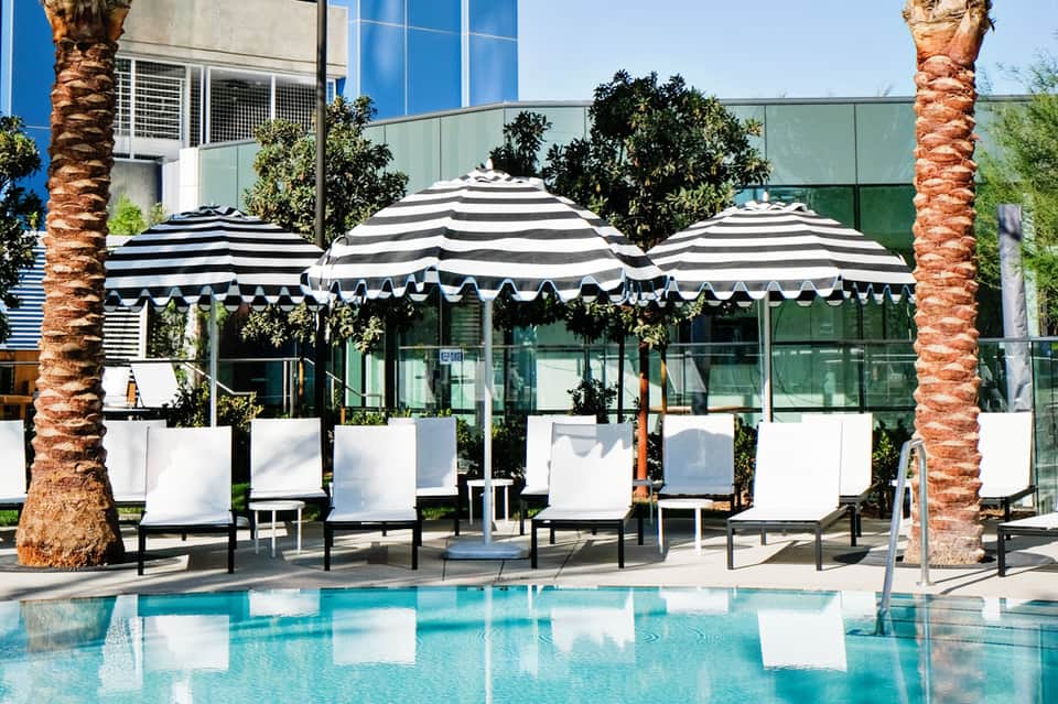 Striped umbrellas and lounge chairs by resort swimming pool