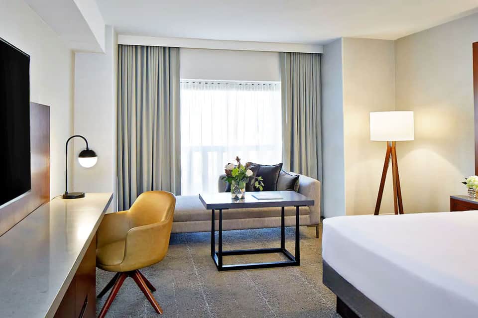 Modern hotel room with seating area, large windows with ocean view, and contemporary furnishings