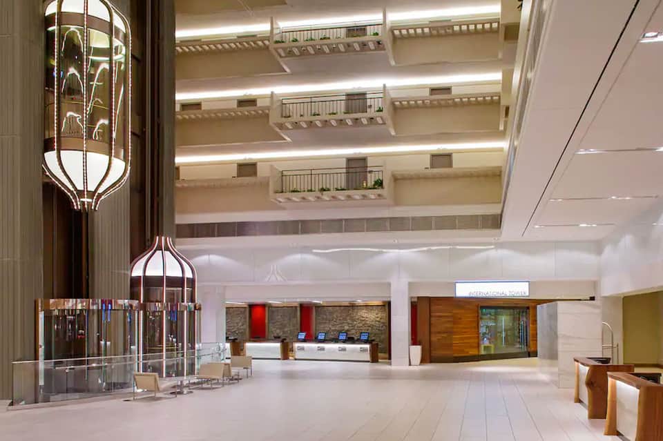 Modern hotel lobby with multi-level balconies, ornate chandelier, and marble floors