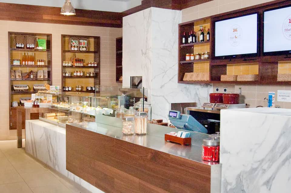 Luxury spa retail counter with marble surfaces, wooden shelving, and product displays