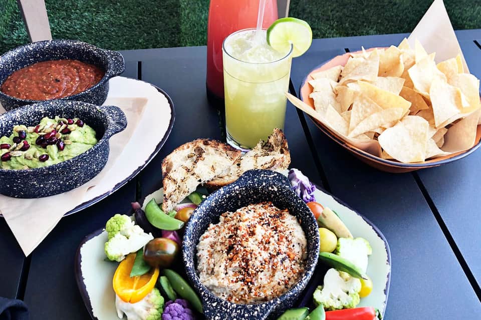 Poolside Mexican food spread with guacamole, salsa, chips, and margarita cocktail