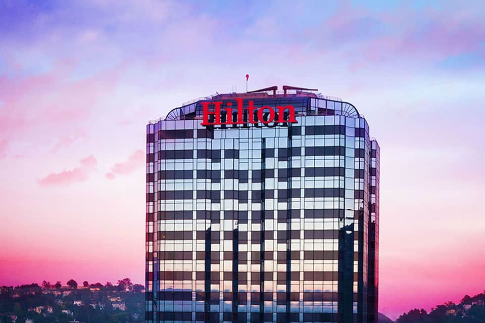 Hilton hotel building at dusk with pink and purple sky