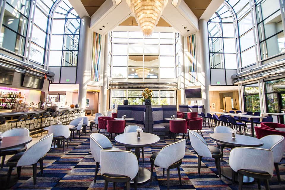 Modern hotel lobby with high ceilings, chandelier, and contemporary seating areas