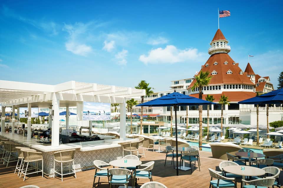 Historic red-brick hotel with cupola, poolside lounge area with blue umbrellas and white pergola